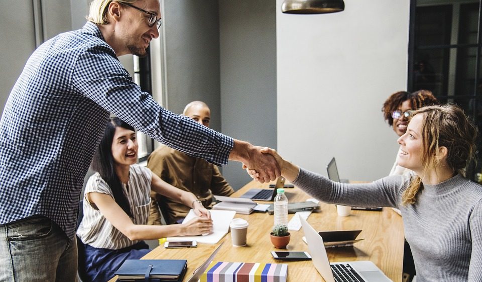 Man and woman shaking hands in an office, highlighting a successful agreement or partnership.