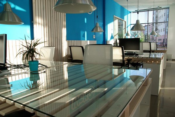 Office space featuring a glass table and walls with a touch of blue.
