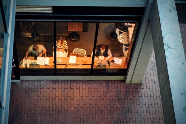 Two men and a woman working near a glass window under dim lighting.