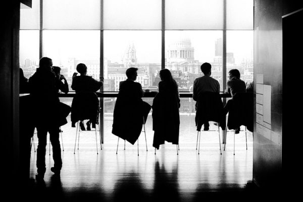 A group of coworkers is depicted in a black and white picture in the office.
