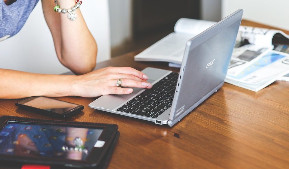 Woman working on her laptop, with her tablet placed next to her.