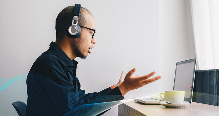 man wearing headphones and talking in front of a laptop