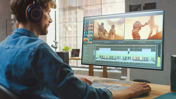 man wearing headphones editing video on a computer